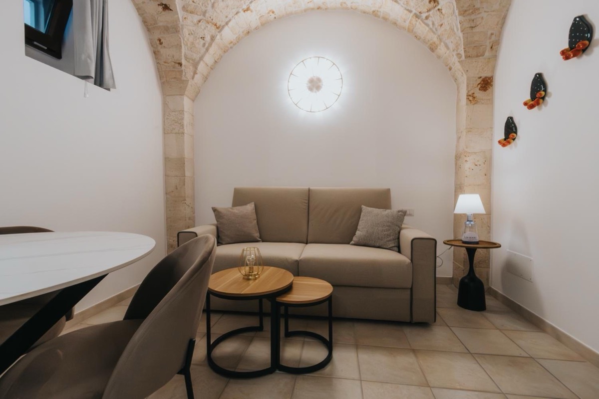 Il divano del soggiorno sotto un arco in pietra, con i conci a vista