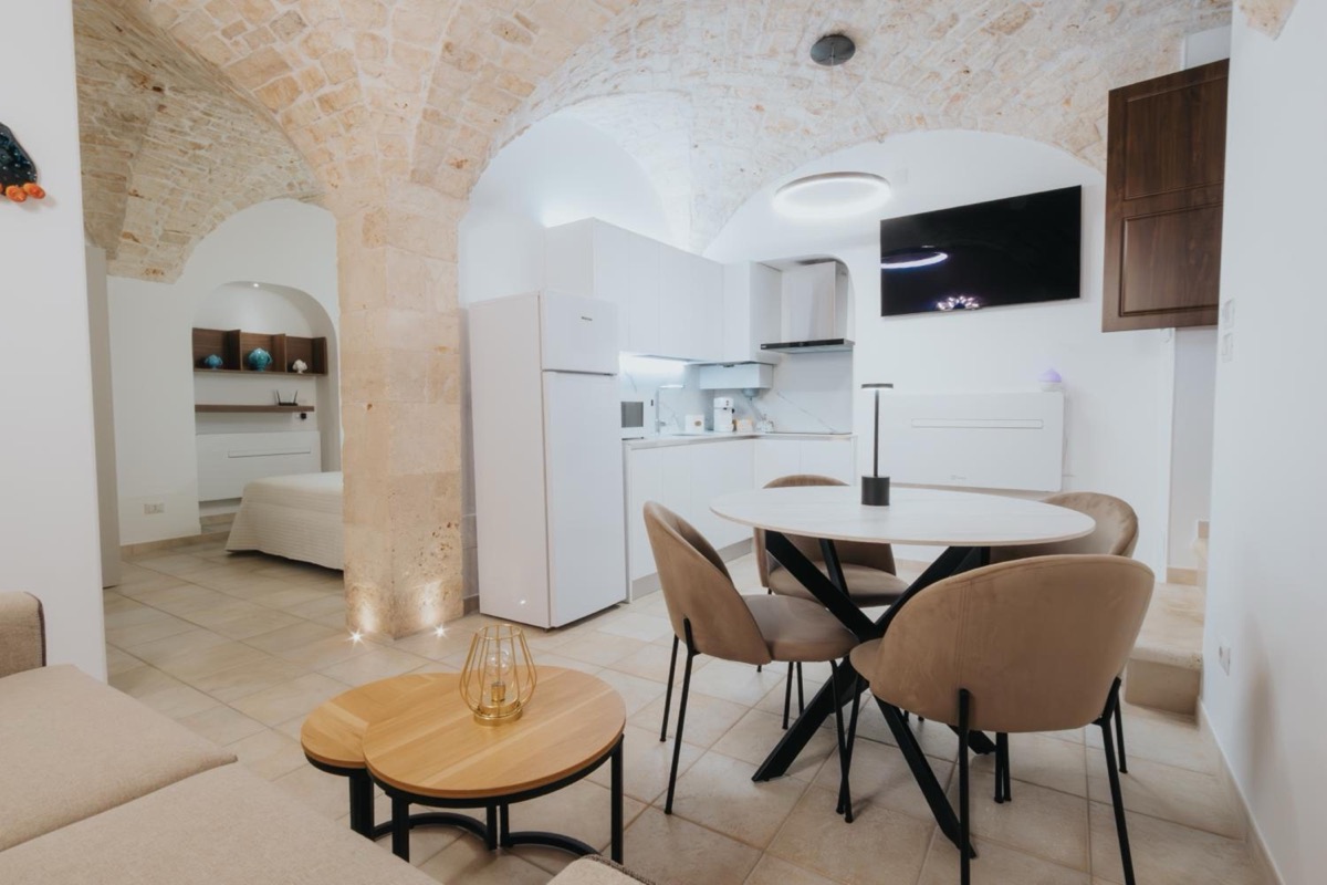 Il soggiorno con la cucina sotto le volte in pietra; in fondo, oltre l’arco, la camera